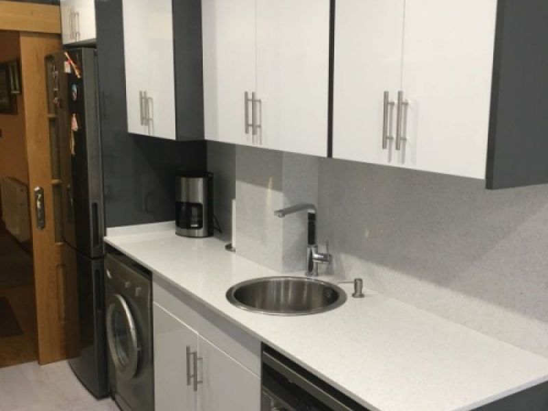 Muebles de cocina de madera de color gris y encimera en blanco