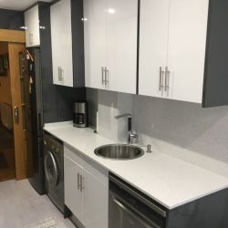 Muebles de cocina de madera de color gris y encimera en blanco